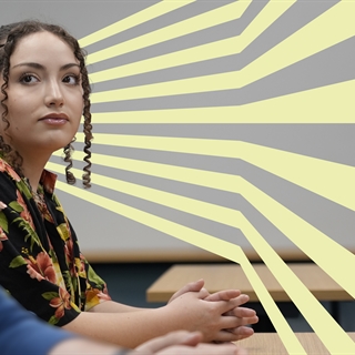 woman sits with hands folded on table