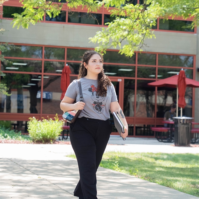 Female student walks through the courtyard in a gray shirt and black pants
