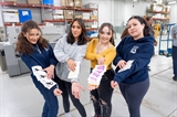 Four female students in the Graphic Design Club show off printed stickers they designed