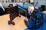 two students sit at a table in the WCTC Student Center playing an oversized game of Connect 4