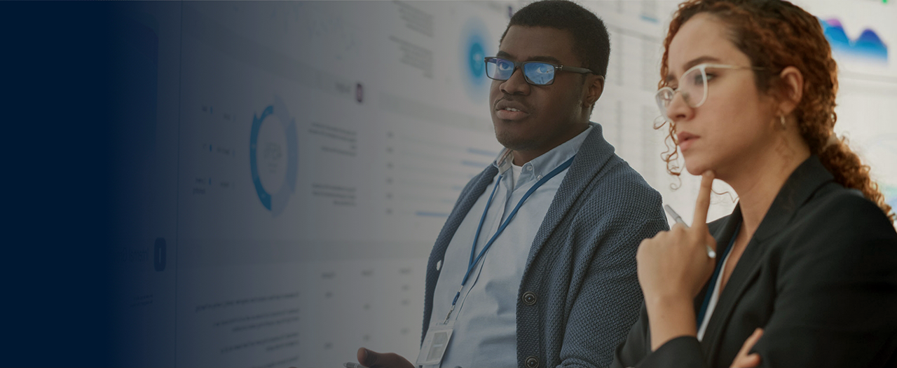 Two students standing in front of a computer screen showing data