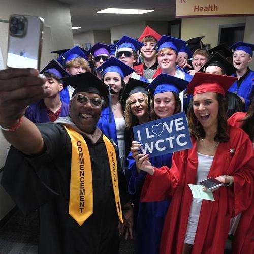 Dual Enrollment Academy graduates taking group selfie in caps and gowns