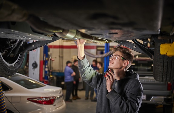 Automotive student inspecting car