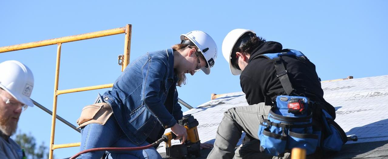 Students working on roof in construction gear