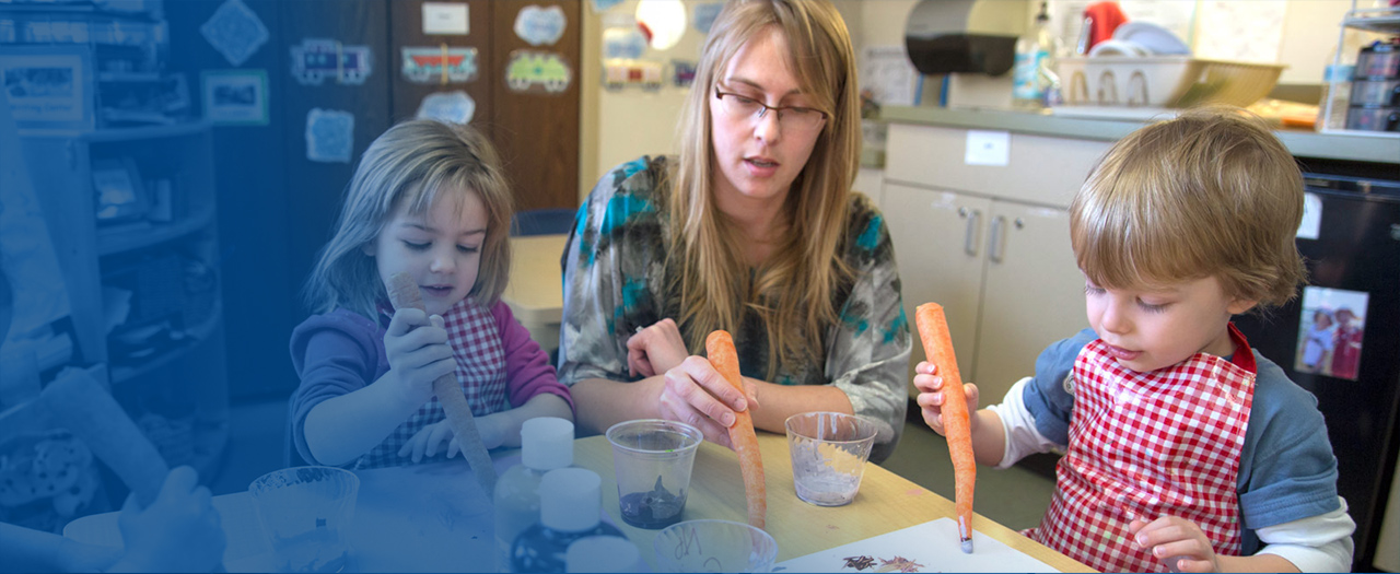 Early childhood teacher and students painting with carrots