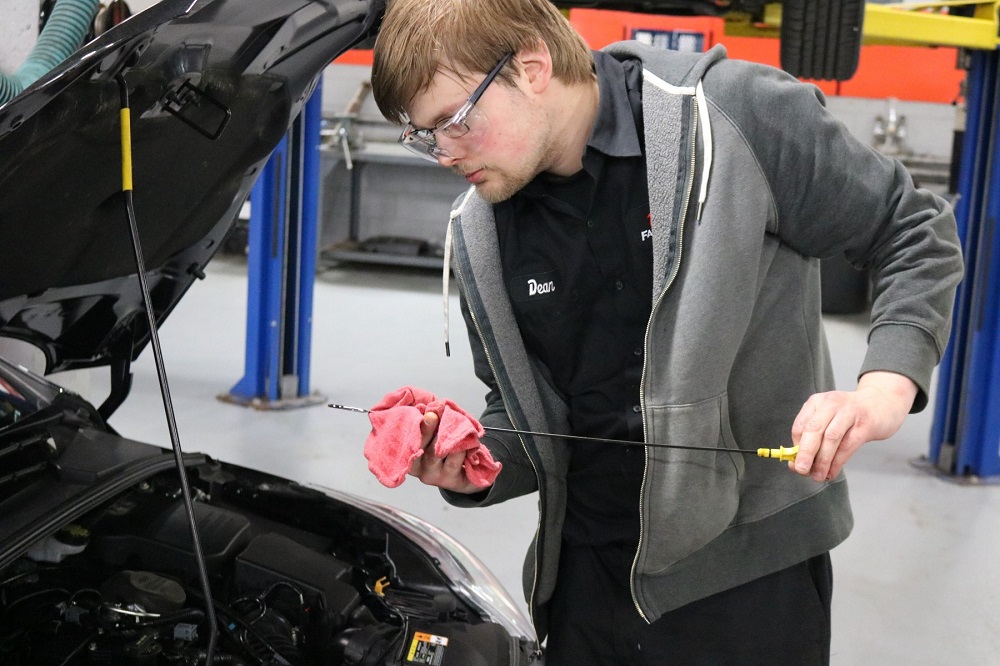 Student checking oil dipstick