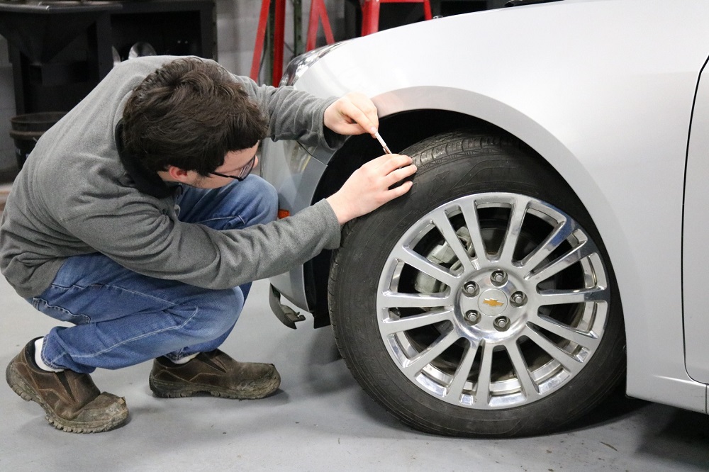 Student checking car tire tread